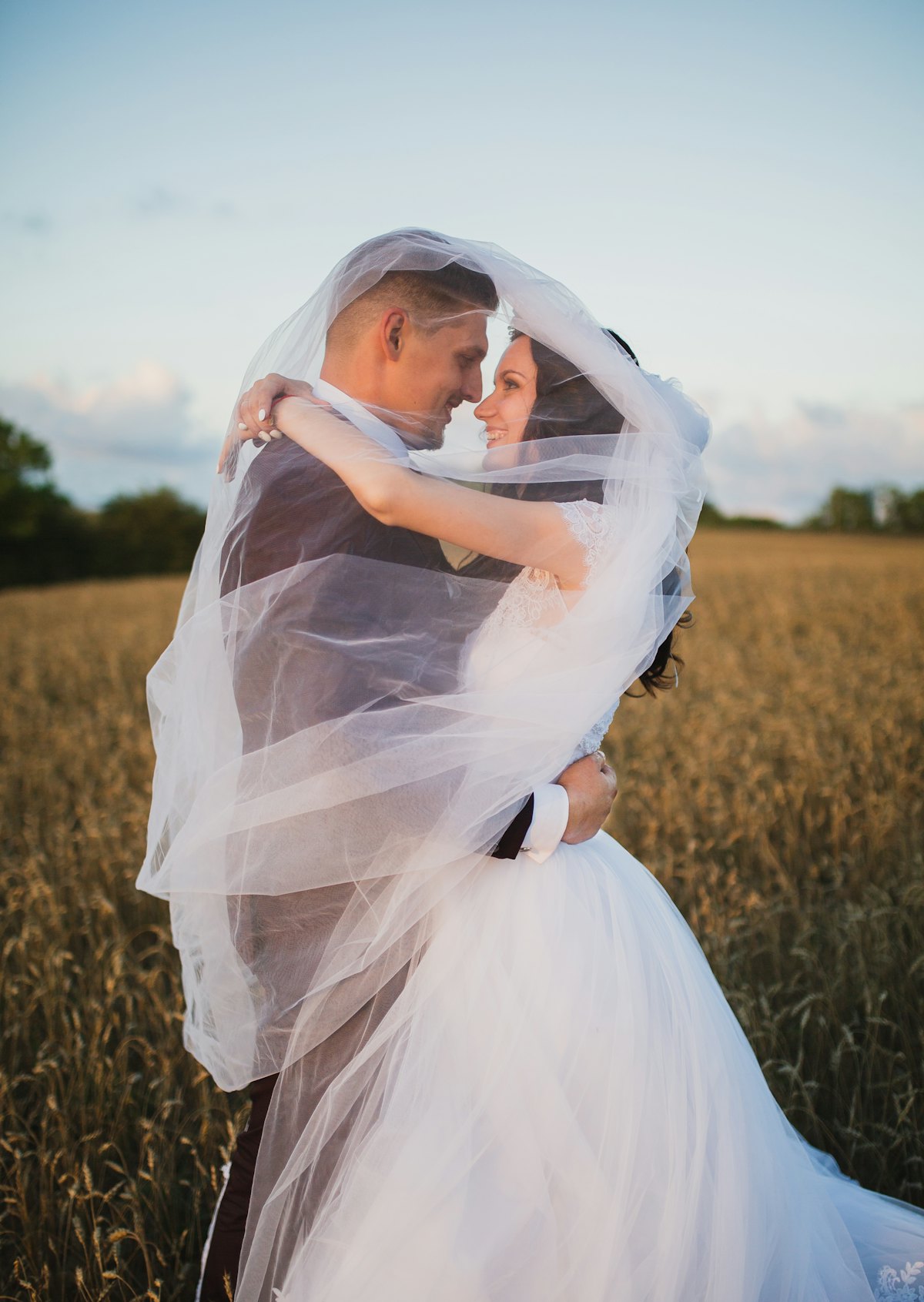 Recién casados sonriendo en un campo verde