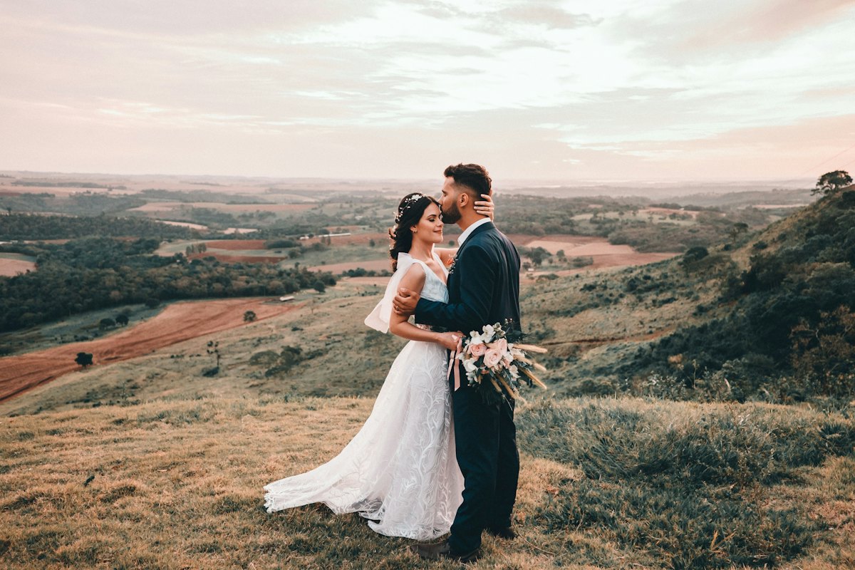 Recién casados besándose en un campo al aire libre
