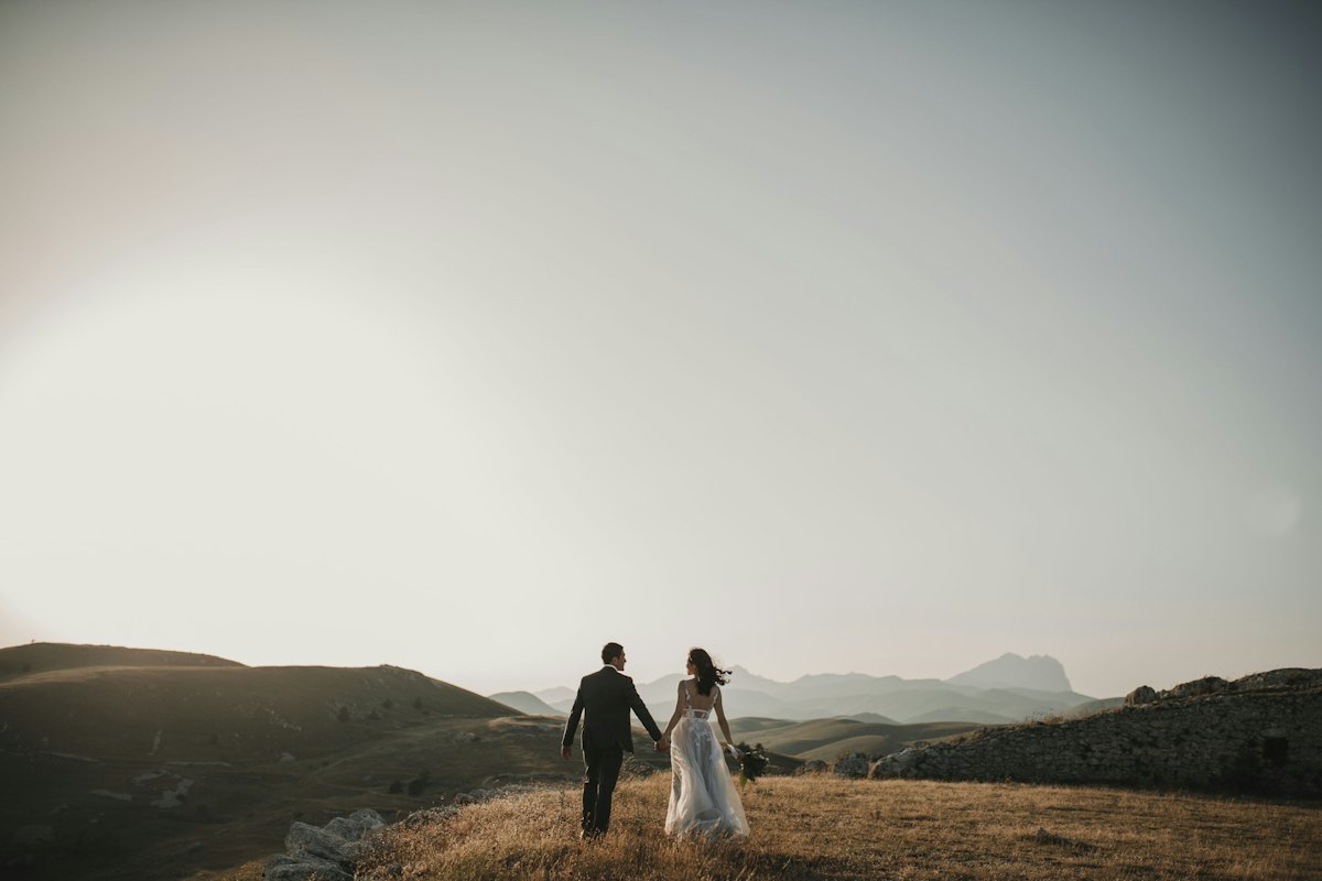 Novios caminando juntos por una colina